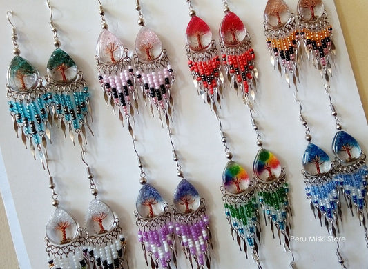 Peruvian handmade beaded dangle earringsl. Each pair features a clear resin top containing a small tree of life design, decorated with colorful beads in various patterns and color combinations.