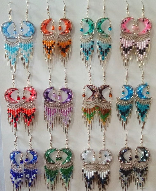Handmade bohemian crescent moon and star dangle earrings displayed on a light background. The earrings feature colorful crescent moons, beaded fringe, and dangling silver colored ends.